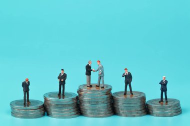 Minyatür insanlar: para istifleme podyum üzerinde duran bir grup işadamı arka plan olarak kullanmak