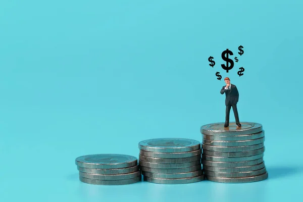 Personas en miniatura: hombre de negocios de pie en el podio de apilamiento de monedas con símbolo de signo de dólar uso como fondo — Foto de Stock