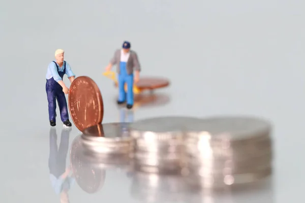 Personas en miniatura: trabajador con monedas, concepto de negocio utilizando como fondo — Foto de Stock