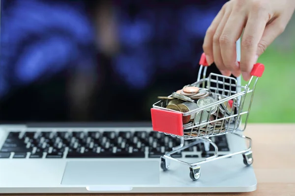 Carro y monedas con la mano humana en el ordenador, idea para compras y pago en línea utilizando como fondo de negocios —  Fotos de Stock