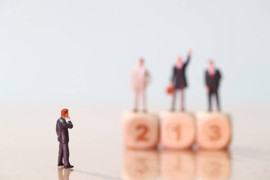 Minyatür insanlar: işadamı görünümlü ve ahşap podyumda rakip ayakta düşünme (finansal ve Iş Yarışması kavramı