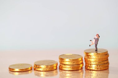 Minyatür insanlar: arka plan olarak kullanarak altın sikke, tasarruf ve yatırım kavramı istifleme üzerinde çift ayakta