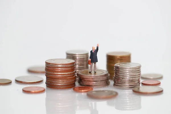 Personas en miniatura: hombre de negocios de pie en el apilamiento de monedas, concepto de competencia financiera y empresarial utilizando como fondo — Foto de Stock