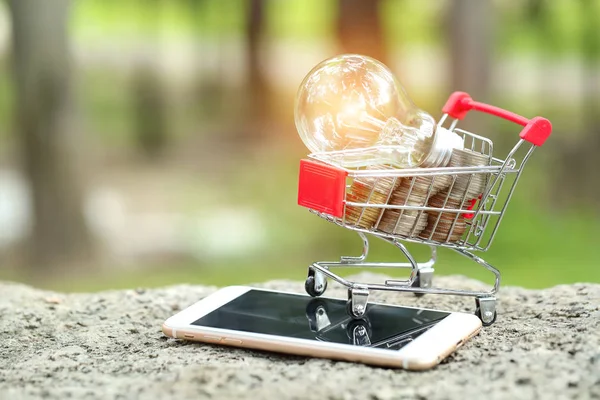 trolley with coins, cell phone and electric glass bulb, idea for shopping and online payment using as business background