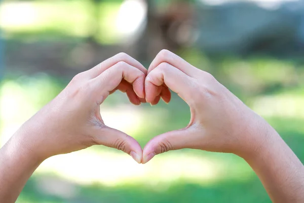 Human hands doing heart symbol on nature background — Stock Photo, Image