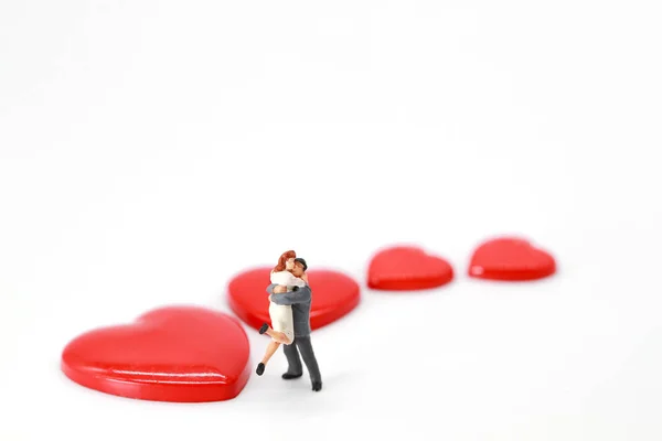 Miniature people: a couple standing on white background with heart symbol, idea for love and valentines day — Stock Photo, Image