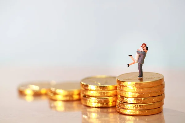 Miniaturmenschen: Paar steht auf Goldmünzen stapeln, Sparen und Anlagekonzept als Hintergrund nutzen — Stockfoto