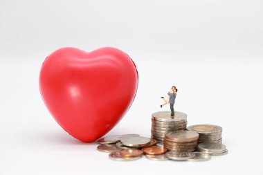 Minyatür insanlar: bir çift okumak kalp sembolü ile sikke istifleme ayakta , lov için para tasarrufu için fikir