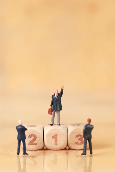 Pessoas em miniatura: empresário de pé com pódio de madeira usando como pano de fundo (Concorrência financeira e empresarial conceito ) — Fotografia de Stock