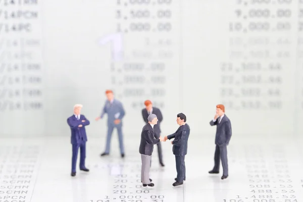 Personas en miniatura: un grupo de hombres de negocios de pie en el banco de libros (esta imagen para el concepto de competencia financiera y empresarial — Foto de Stock