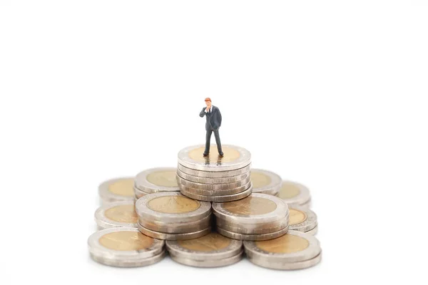 Personas en miniatura: hombre de negocios de pie en el apilamiento de monedas, concepto de competencia financiera y empresarial utilizando como telón de fondo — Foto de Stock