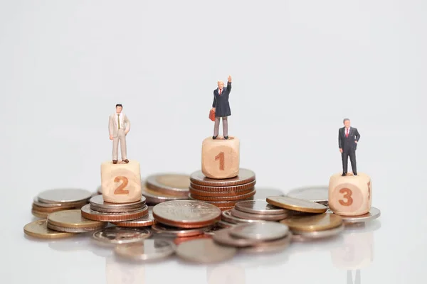 Personas en miniatura: hombre de negocios de pie en el apilamiento de monedas, concepto de competencia financiera y empresarial utilizando como fondo — Foto de Stock