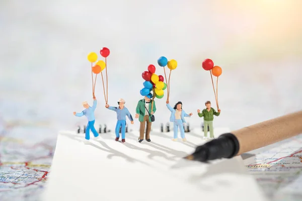 Miniature family: a group of happy family holding balloon using map and travel on holiday idea of family day concep