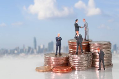 Minyatür insanlar: şehir bulanıklığı arka plan ile sikke istifleme podyum üzerinde duran işadamı (mali ve iş rekabet konsepti için bu görüntü