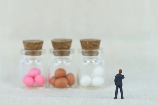 Μινιατούρα επιχειρηματίας κοιτάζει τα πασχαλινά αυγά. Πώς να κάνουμε επιχειρήσεις με Πασχαλινά αυγά? — Φωτογραφία Αρχείου