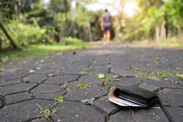 adam sokakta yürürken ya da içinde banknot ile parkta çalışan onun deri cüzdan kaybetti