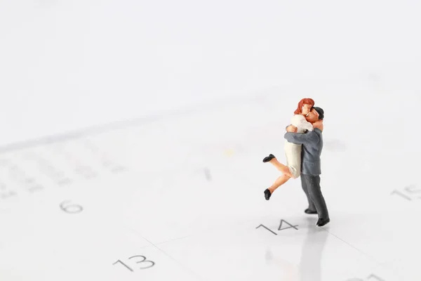 Pessoas em miniatura: um casal de pé no calendário em 14 de fevereiro, significado de amor — Fotografia de Stock