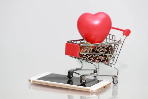 Wózek z monet i serca na inteligentny telefon, pomysł na zakupy i płatności online za pomocą jako tło biznesowe — Zdjęcie stockowe