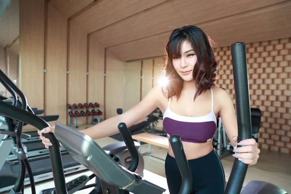 Retrato de una joven mujer sana y deportiva usando una máquina de ejercicio en el gimnasio (esta imagen para el concepto de fitness y entrenamiento) — Foto de Stock