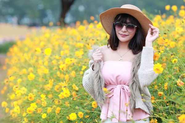 Cute and beautiful girl with hat standing in nature outdoors among cosmos flowers field (rest time on vacation concept) — Stock Photo, Image