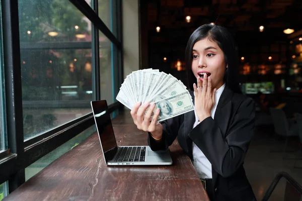 Успішна і щаслива бізнес-леді з комп'ютером, що показує банкноту і кажуть вау — стокове фото