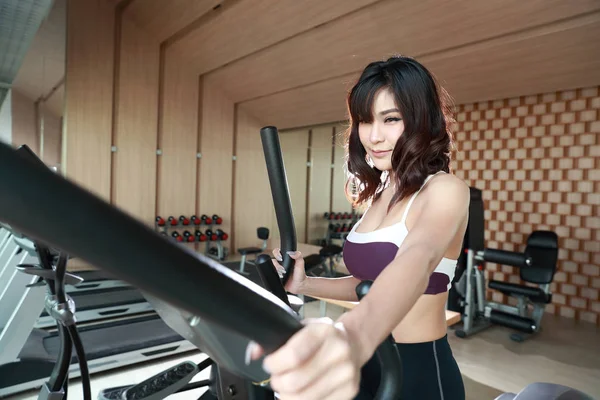 Retrato de una joven mujer sana y deportiva usando una máquina de ejercicio en el gimnasio (esta imagen para el concepto de fitness y entrenamiento) — Foto de Stock