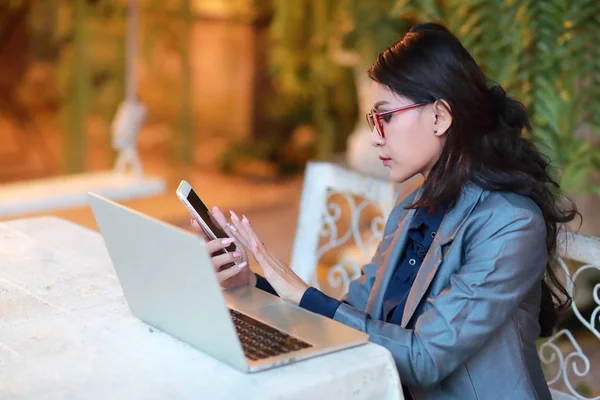 Söt och charmig affärskvinna med glasögon som arbetar på bärbar dator och mobiltelefon från restaurang eller kafé — Stockfoto