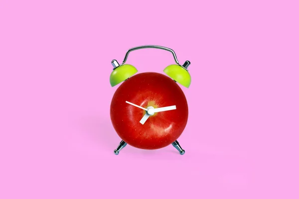 Jabłko w budziku na różowy pastel biurko — Zdjęcie stockowe