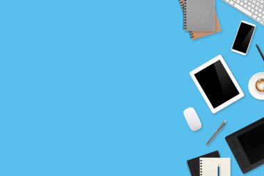 Grafik tasarımcı masaüstü görüntüsü dizüstü bilgisayar, kalem ekranı, tablet stili, ofis malzemeleri ve mavi pastel arka planda kahve fincanı ile çalışıyor.