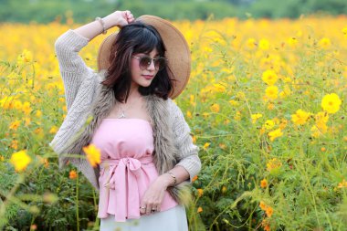 kozmos çiçek alanı arasında doğada açık havada duran şapka ile sevimli ve güzel kız (tatil kavramı dinlenme zamanı)