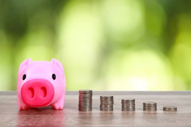 doğa arka plan ile ahşap masa üzerinde yığın sikke ile piggy