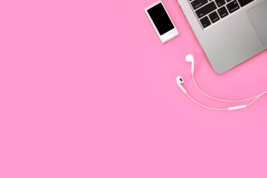 akıllı telefon, müzik çalar, kulak telefonu ve pembe pastel arka plan üzerinde bilgisayar ile teknoloji çalışma iş masasında mola