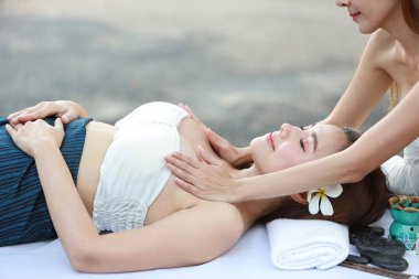 Göğüs masajı, iki güzel ve seksi Asyalı kadının yan görünüm portresi, uzun saçlı, beyaz elbiseli, yaz tatili boyunca uzanan yağ masajı salonunun keyfini çıkaran.
