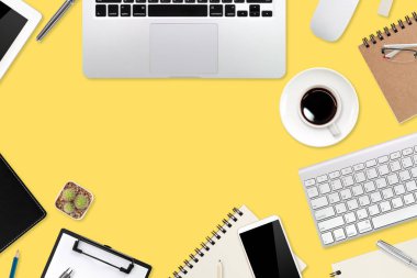 Düz çalışma masası dizüstü bilgisayarı, ofis malzemeleri, kahve fincanı, tablet ve cep telefonu sarı pastel arka planda.