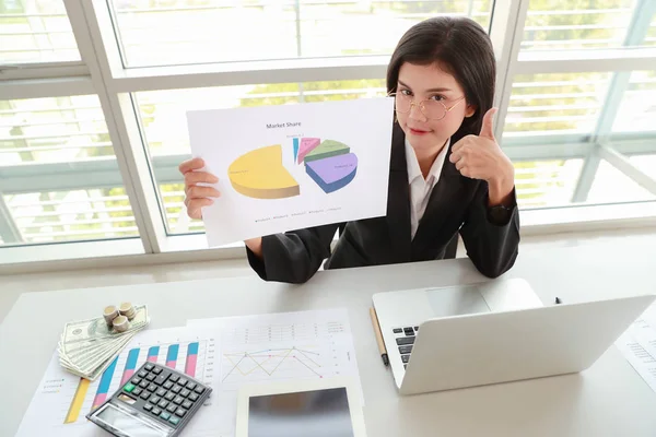 businesswoman showing thumb up and company profit with graph in meeting room