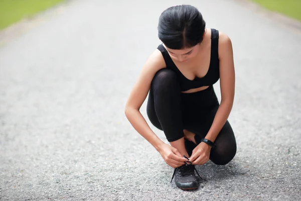 Mujer joven atando zapatos de correr — Foto de Stock