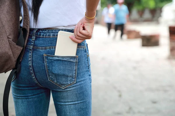 Asiático viajante mulher no antigo templo com mochila e segurando celular no bolso jean — Fotografia de Stock