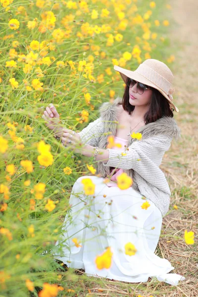 Roztomilá a krásná dívka s kloboukem v přírodě mezi květinami Kosmos (odpočinek na dovolené) — Stock fotografie