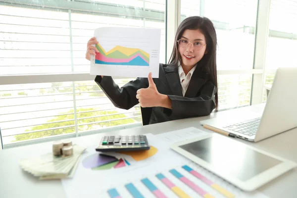 Businesswoman showing thumb up and company profit with graph in meeting room — Stock Photo, Image