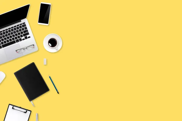 Mesa de trabalho de marketing digital com computador portátil, material de escritório, xícara de café e telefone celular no fundo pastel amarelo — Fotografia de Stock