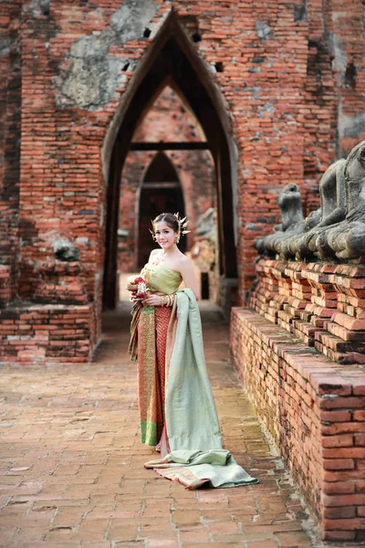 Moda Asian Girl w Thai tradycyjny kostium w starożytnej świątyni z kierownicy kwiat w ręku — Zdjęcie stockowe