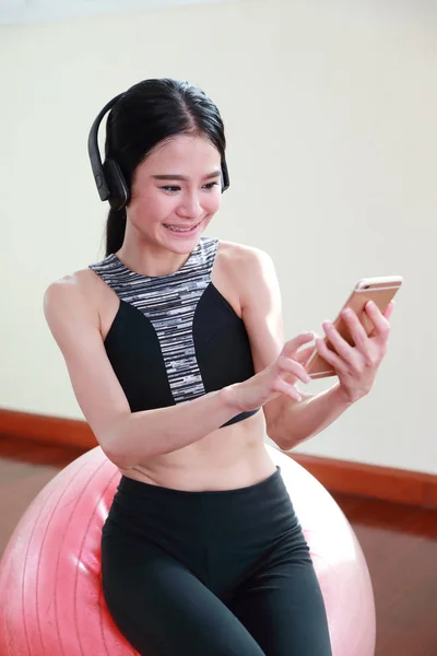 Молода здорова і спортивна жінка слухає музику з мобільного телефону в спортзалі — стокове фото