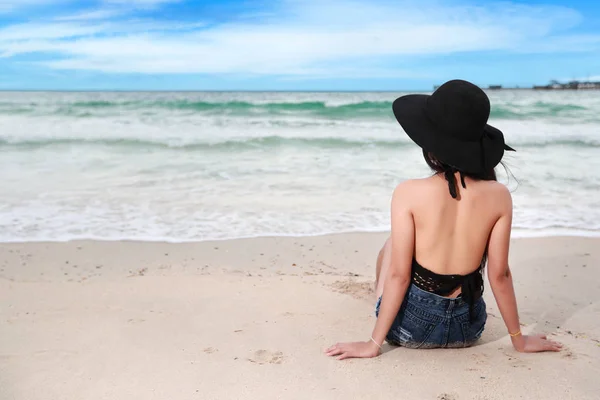 Back view retrato da moda e menina sexy com chapéu preto na praia e céu azul — Fotografia de Stock