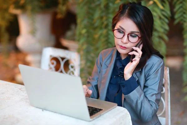 Restoran veya kafeden dizüstü bilgisayar ve cep telefonu üzerinde çalışan gözlüklü sevimli ve büyüleyici iş kadını — Stok fotoğraf