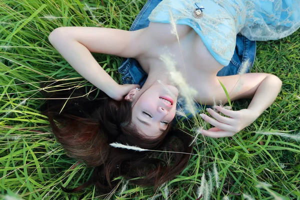 Портрет красивої жінки, що лежить у полі трави з щасливим обличчям — стокове фото