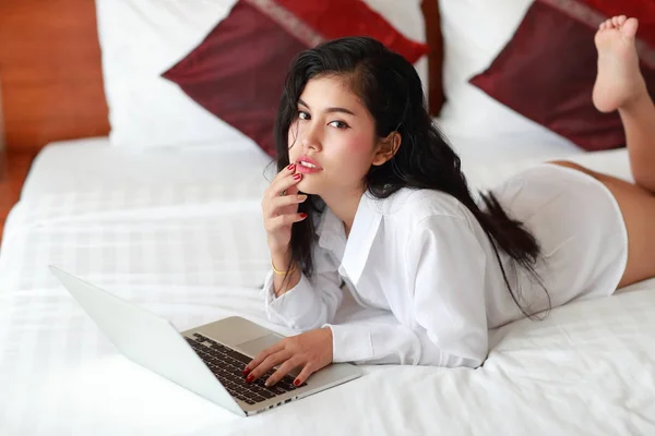 Σέξι Ασιάτης/ισσα νεαρή γυναίκα φορώντας λευκό πουκάμισο ξαπλωμένο στο κρεβάτι και κοιτάζοντας κάποιον με σέξι μάτια και τα χείλη — Φωτογραφία Αρχείου