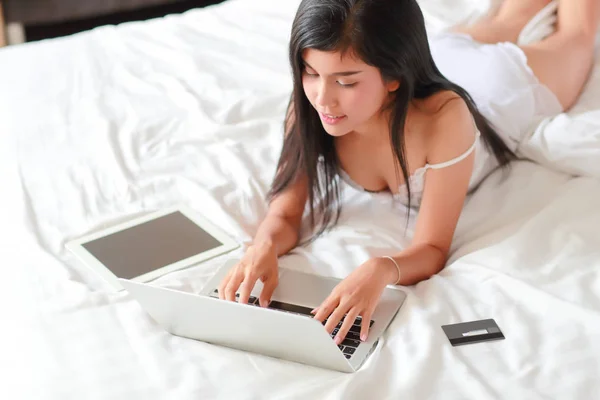 Beautiful and sexy woman shopping and online payment by using computer and tablet in bedroom with credit card — Stock Photo, Image