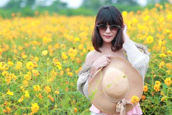 Cute and beautiful girl with hat standing in nature outdoors among cosmos flowers field (rest time on vacation concept) — Stock Photo, Image