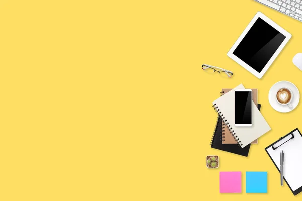 Technológiai íróasztal laptop számítógéppel, irodai eszközök, kávéscsésze és a mobiltelefon a sárga pasztell háttér — Stock Fotó