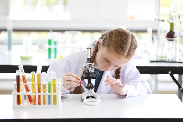 Niña curiosa está experimentando la ciencia con microscopio y cara de atención (concepto de educación y científico) — Foto de Stock